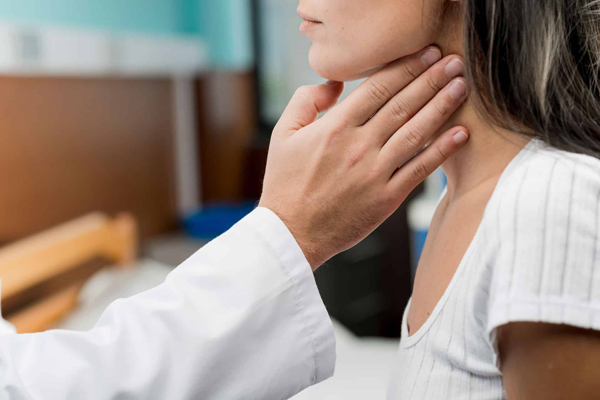 een vrouw die haar nek laat onderzoeken door een dokter.