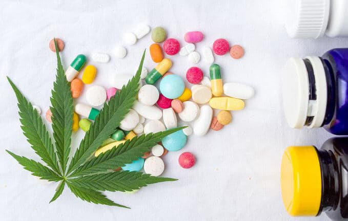 een marihuanablad naast pillen en een flesje medicijnen.