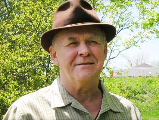 een oudere man met een hoed op in een veld.